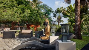 A Buddha statue surrounded by outdoor furniture and a decorative snake sculpture. - Domaine de Néron - Daïquiri (Le Moule)