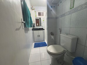 Uma casa de banho compacta com sanita, chuveiro e lavatório.