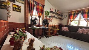 A living room with a sofa, a coffee table, and decorative items. There are two fans on the table, a fireplace, and a TV mounted on the wall. - Beach house in São José da Coroa Grande, with Wi-Fi and TV. (São José da Coroa Grande)