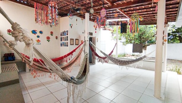 A room with multiple hammocks hanging from the ceiling, a tiled floor, and a view of the outdoors. - Beach house in São José da Coroa Grande, with Wi-Fi and TV. (São José da Coroa Grande)