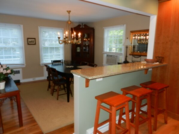A kitchen with a bar area, wooden chairs, and a chandelier. - In-town jewel -- Vineyard Haven (Vineyard Haven)