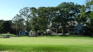 Um campo de golfe com bunkers de areia, um clube e casas residenciais ao fundo.