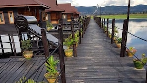 Eine hölzerne Pier, die zu einer Reihe von Ferienhäusern führt, mit Blumentöpfen entlang der Seiten.