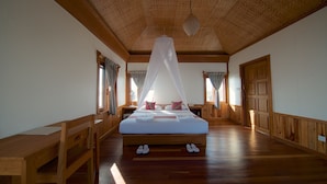 Ein geräumiges Schlafzimmer mit einem großen Bett, Holzboden und einer hohen Decke mit sichtbaren Holzbalken.