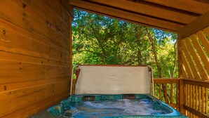 Un bain à remous avec une terrasse en bois et une vue sur les arbres.