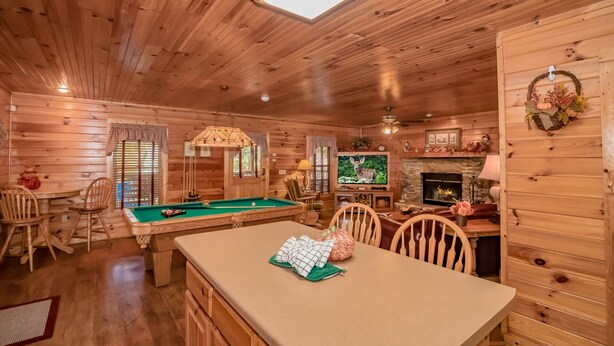 A cozy cabin interior with a pool table, wooden walls, a television, and a fireplace. - SugarShack: Private, Wooded, Honeymoon, Hot Tub, Game Room, Wifi, near Dollywood (Sevierville)