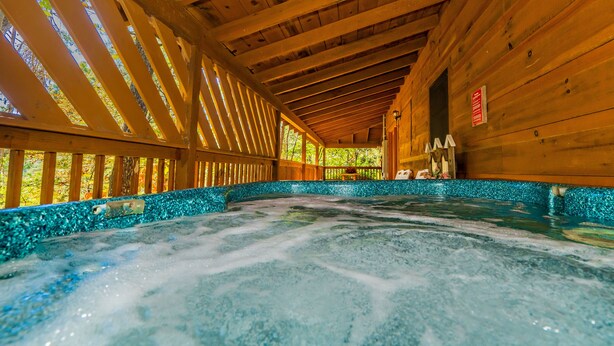 Un spa en bois doté d’un jacuzzi, le tout entouré d’une bordure en mosaïque turquoise.