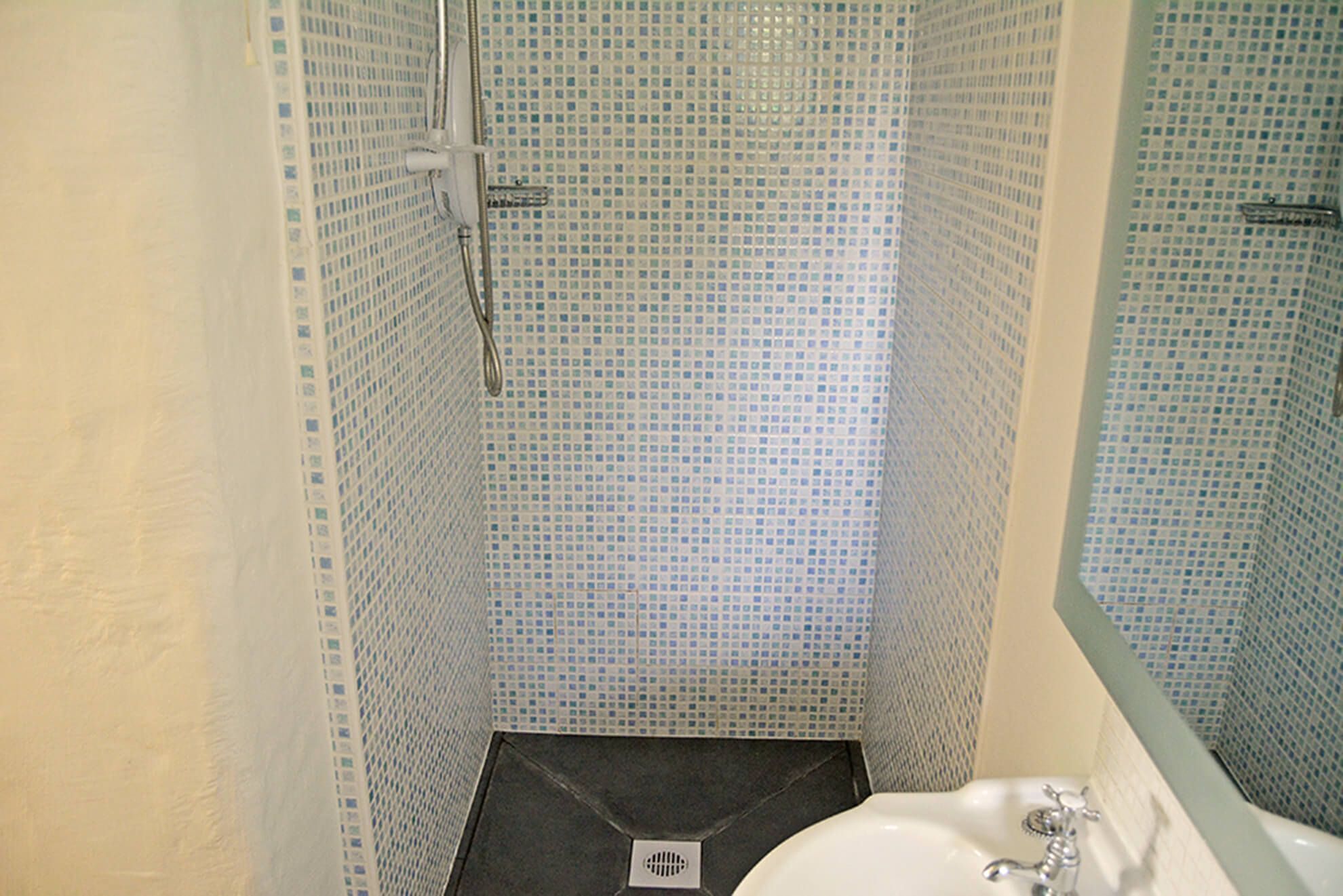 A bathroom with a shower, tiled walls, and a sink.
