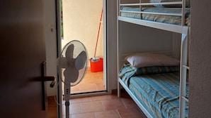 A small, single-room apartment with a bunk bed, a standing fan, a mop, and a door leading to an outdoor area. - Marina di Bravone beach, Linguizzetta, Corsica, France (Linguizzetta)
