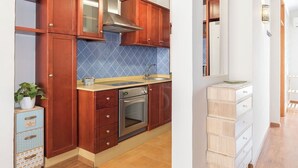 A kitchen with wooden cabinets, a stainless steel oven, and a blue tiled backsplash.
