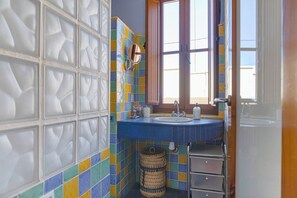 Een badkamer met een blauwe wastafel, een spiegel en een raam.