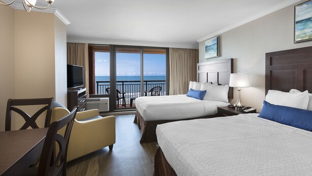 A hotel room with two beds, a TV, a desk, and a view of the ocean. - Beautiful Caravelle Resort Oceanfront Double Efficiency (Myrtle Beach)