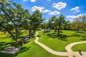 Ein Park mit einem gewundenen Pfad, Picknicktischen und einem Gebäude mit blauem Dach in der Ferne.