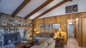 A cozy living room with a stone fireplace, wooden beams, a sofa, and a coffee table. - (19B) Yosemite Retreat in the Meadows at The Redwoods In Yosemite (Wawona)