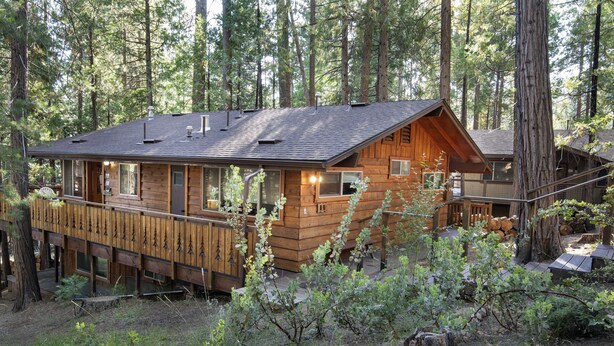 A cabin with a deck, surrounded by forest. - (19B) Yosemite Retreat in the Meadows at The Redwoods In Yosemite (Wawona)