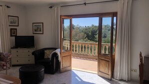 Een ruime woonkamer met balkon, televisie en een bank.