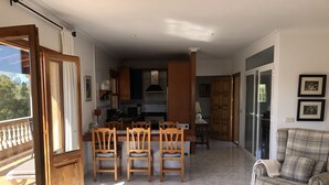 Een ruime woonkamer met een eettafel en stoelen, een bank en uitzicht op de keuken.