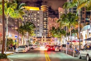 A nighttime urban street with palm trees, buildings, and parked cars. - Spectacular Beach Views, Iconic Ocean Drive, Designer 3 BR/3 BA, Walk Everywhere (Miami Beach)