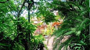 A lush garden pathway leading to a brick building with an archway. - Romantic Zone, best location; with daily maid and cook service included! (Puerto Vallarta)