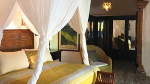 A bed with a canopy, a chair, and a nightstand with a lamp. - Romantic Zone, best location; with daily maid and cook service included! (Puerto Vallarta)