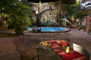 An outdoor patio with a pool, surrounded by plants and a decorative wall. - Romantic Zone, best location; with daily maid and cook service included! (Puerto Vallarta)