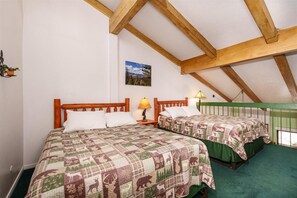 A bedroom with two beds, wooden headboards, a green railing, and a painting on the wall. - (A204) Loft Condominiums (Yosemite National Park)