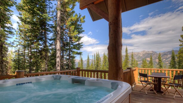 Ein Whirlpool auf einer Holzdiele mit Blick auf die Berge.