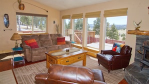 A spacious living room with a fireplace, large windows, and a view of the outdoors. - Cabin, Dog Friendly, Hot Tub, Views, 6 acres, Wheelchair Accessible (Florissant)
