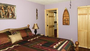 A bedroom with a large bed, a wooden door, a ceiling fan, and a wall-mounted decoration. - Cabin, Dog Friendly, Hot Tub, Views, 6 acres, Wheelchair Accessible (Florissant)