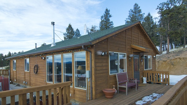 A wooden cabin with large windows, a deck, and a chimney. - Cabin, Dog Friendly, Hot Tub, Views, 6 acres, Wheelchair Accessible (Florissant)