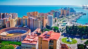Un paysage urbain côtier avec un stade imposant, des immeubles de grande hauteur et une marina.