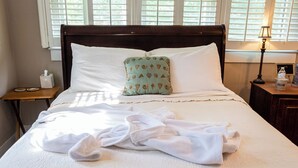 A neatly made bed with white linens, a patterned pillow, and a bedside table with a tissue box and a water bottle. - Guest House of Kentucky (2 Queens - 1st Floor) (Lancaster)