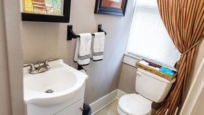 A small bathroom with a white sink, a toilet, and a window with curtains. - Guest House of Kentucky (2 Queens - 1st Floor) (Lancaster)