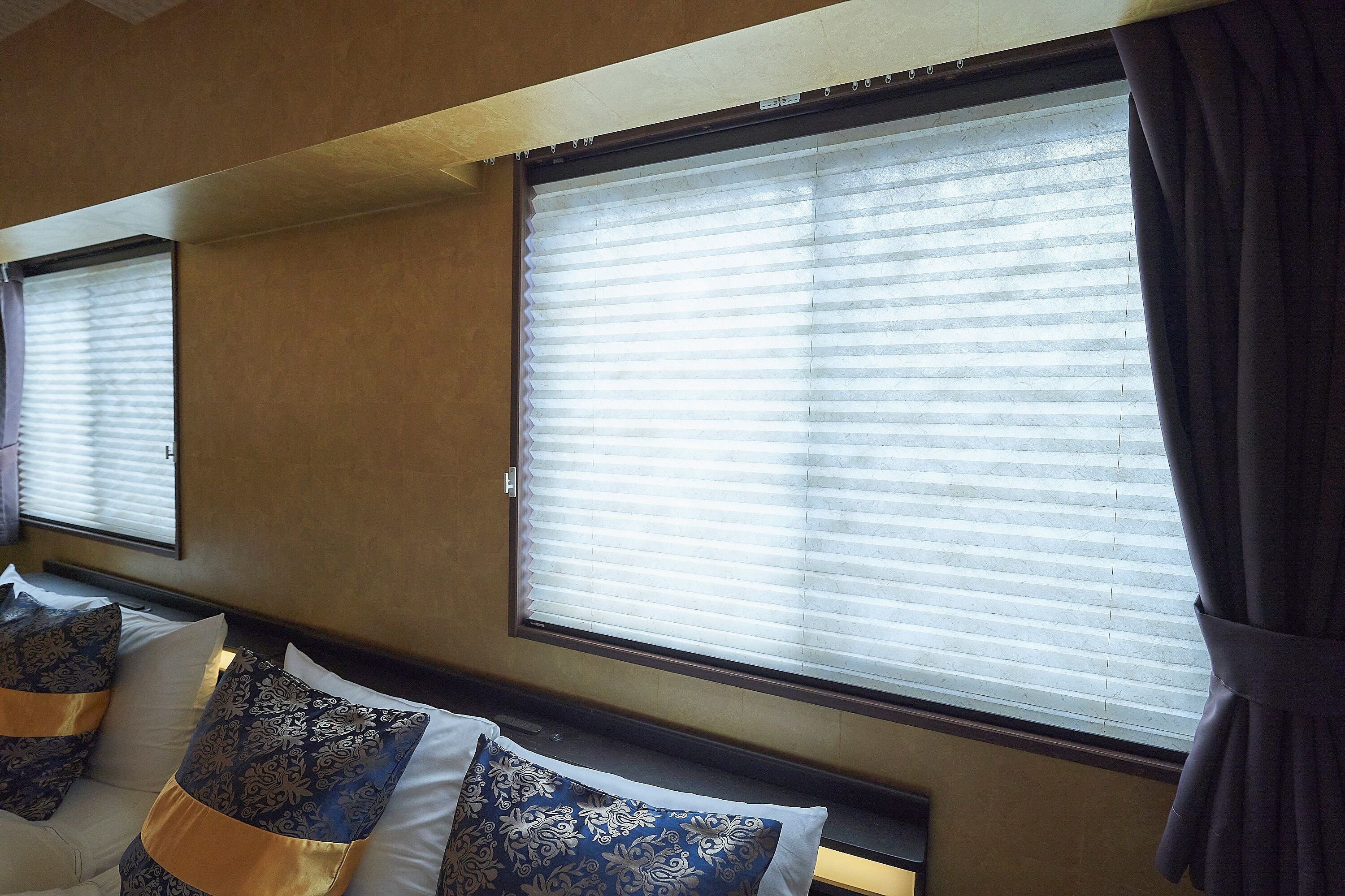 Una habitación de hotel con una cama, dos ventanas con persianas y una cortina.
