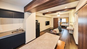 A compact kitchen with a sink, refrigerator, and a flat-screen TV mounted on the wall. - TOKYO Condominiun HOTEL ASAKUSA EIGHT (Tokyo)