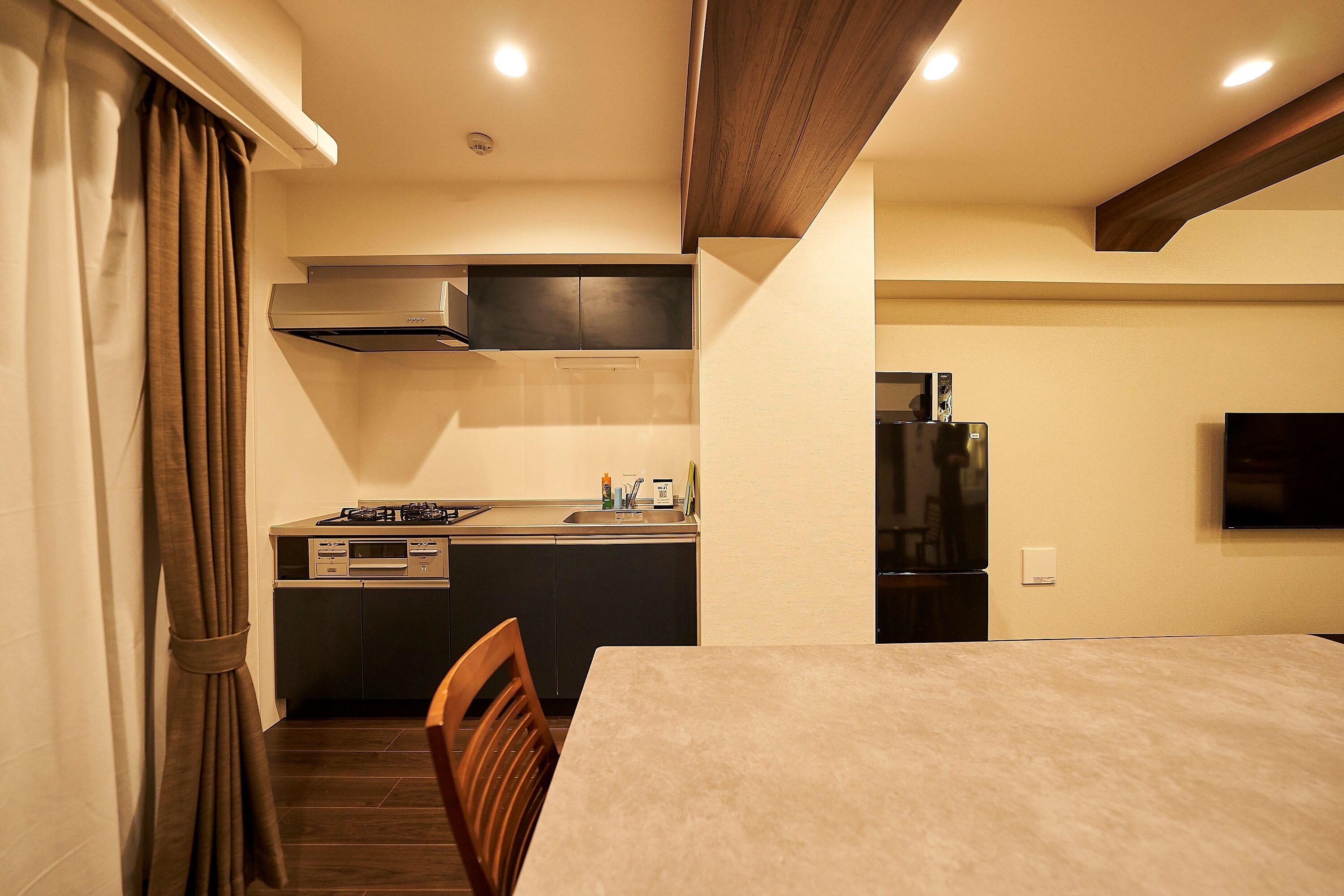 A modern kitchen with dark cabinetry, a built-in stove, and a refrigerator.