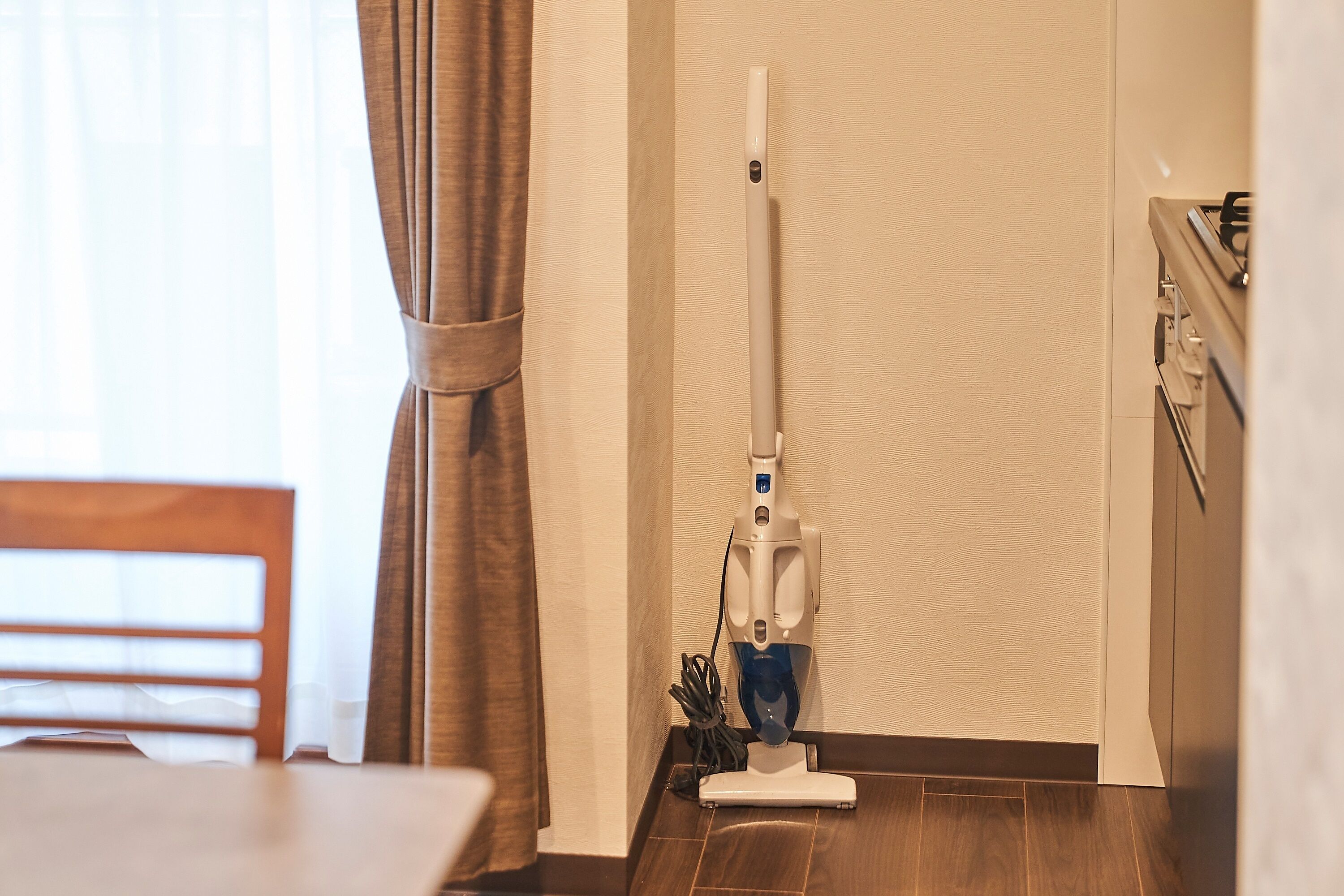 A room with a standing vacuum cleaner, a dining table, and a chair.