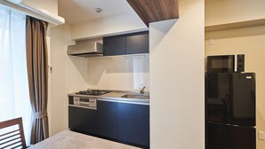 A compact kitchen with a gas stove, sink, and black refrigerator. - TOKYO Condominiun HOTEL ASAKUSA EIGHT (Tokyo)