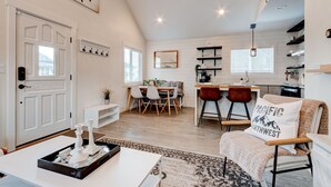 A spacious living room with a dining area, a kitchen, and a cozy seating area with a decorative pillow.