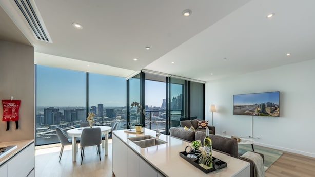 A modern apartment with a kitchen, dining area, and living room, featuring large windows with a city view. - Melbourne Private Apartments - Collins Wharf Waterfront, Docklands (Docklands)
