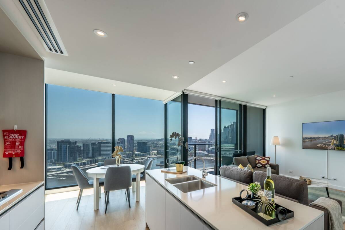 Een modern appartement met keuken, eethoek en woonkamer, met grote ramen en uitzicht over de stad.