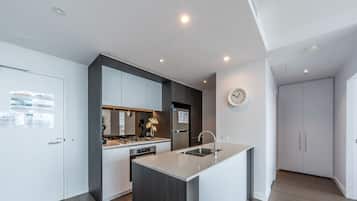 A modern kitchen with a central island, built-in appliances, and a clock on the wall.