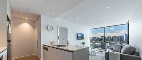 A modern apartment with a kitchen, dining area, and a large window with a city view.