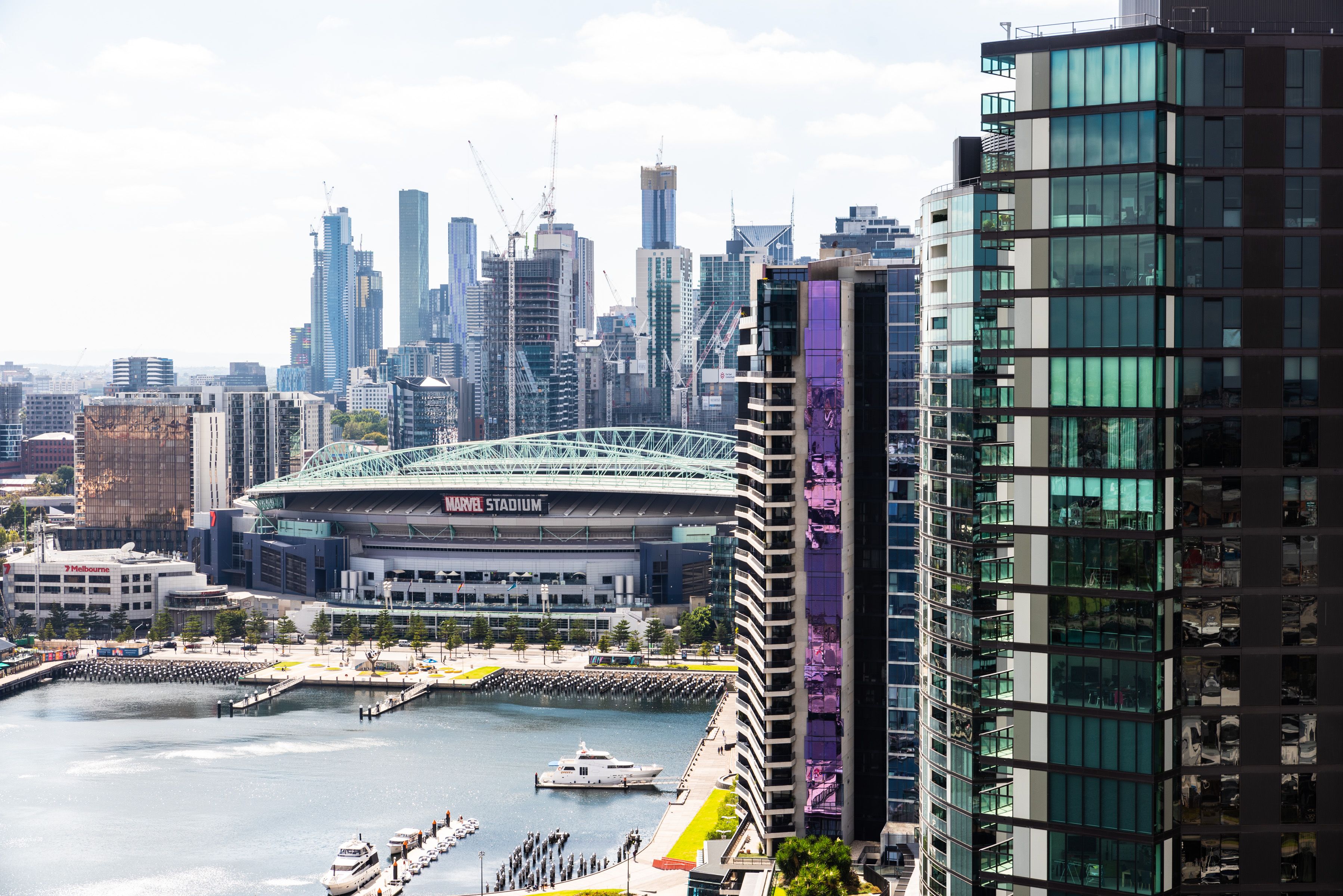 A waterfront view of a city with modern buildings, including a stadium and high-rise structures.