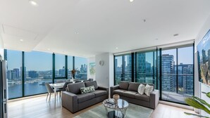 A spacious living room with a city view, a dining area, and a large window. - Melbourne Private Apartments - Collins Wharf Waterfront, Docklands (Docklands)