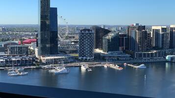 A city skyline with modern buildings, a marina with boats, and a clear blue sky.