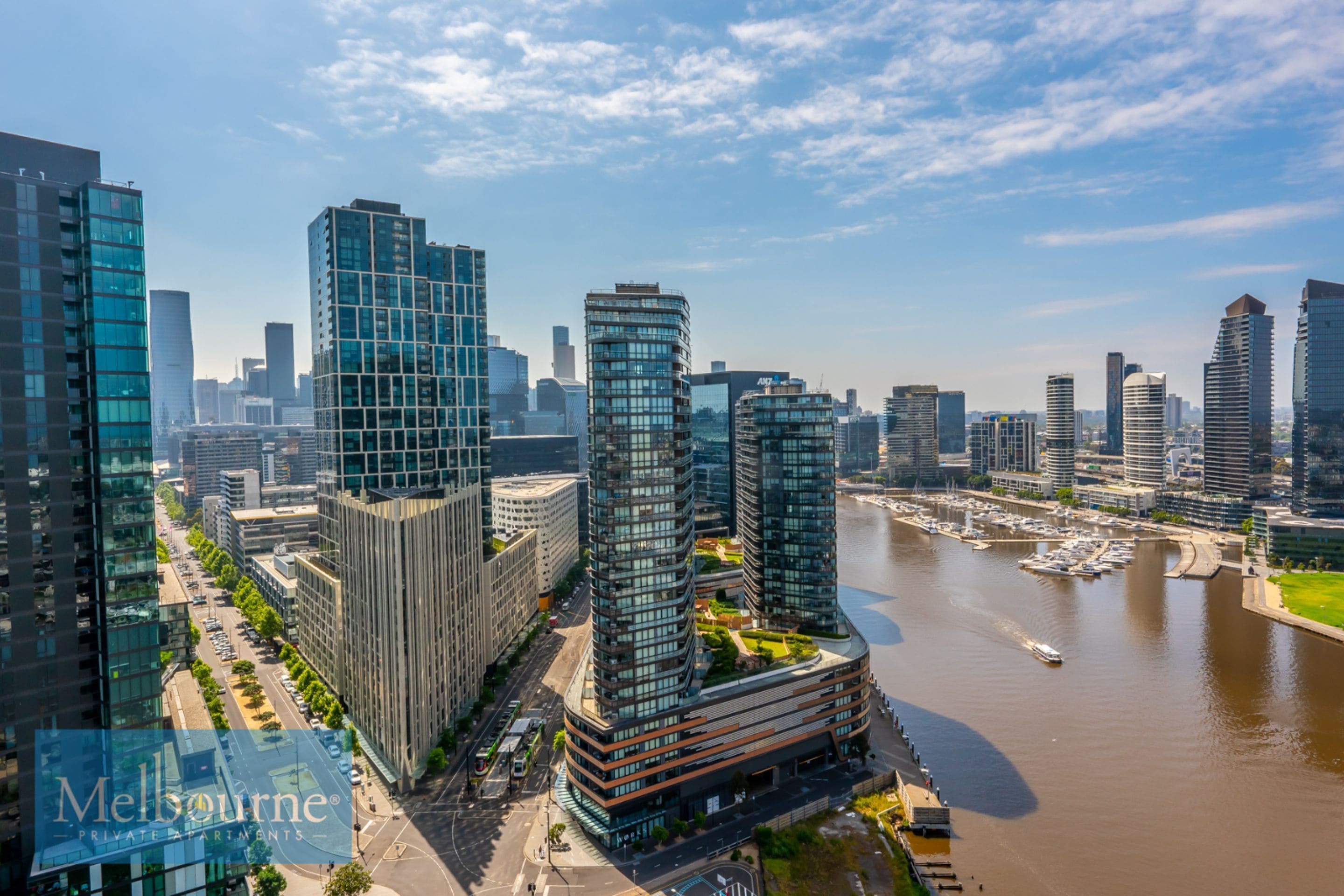 A high-rise building with a modern glass facade, located near a river with a marina.