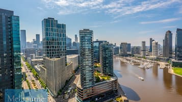 A high-rise building with a modern glass facade, located near a river with a marina.