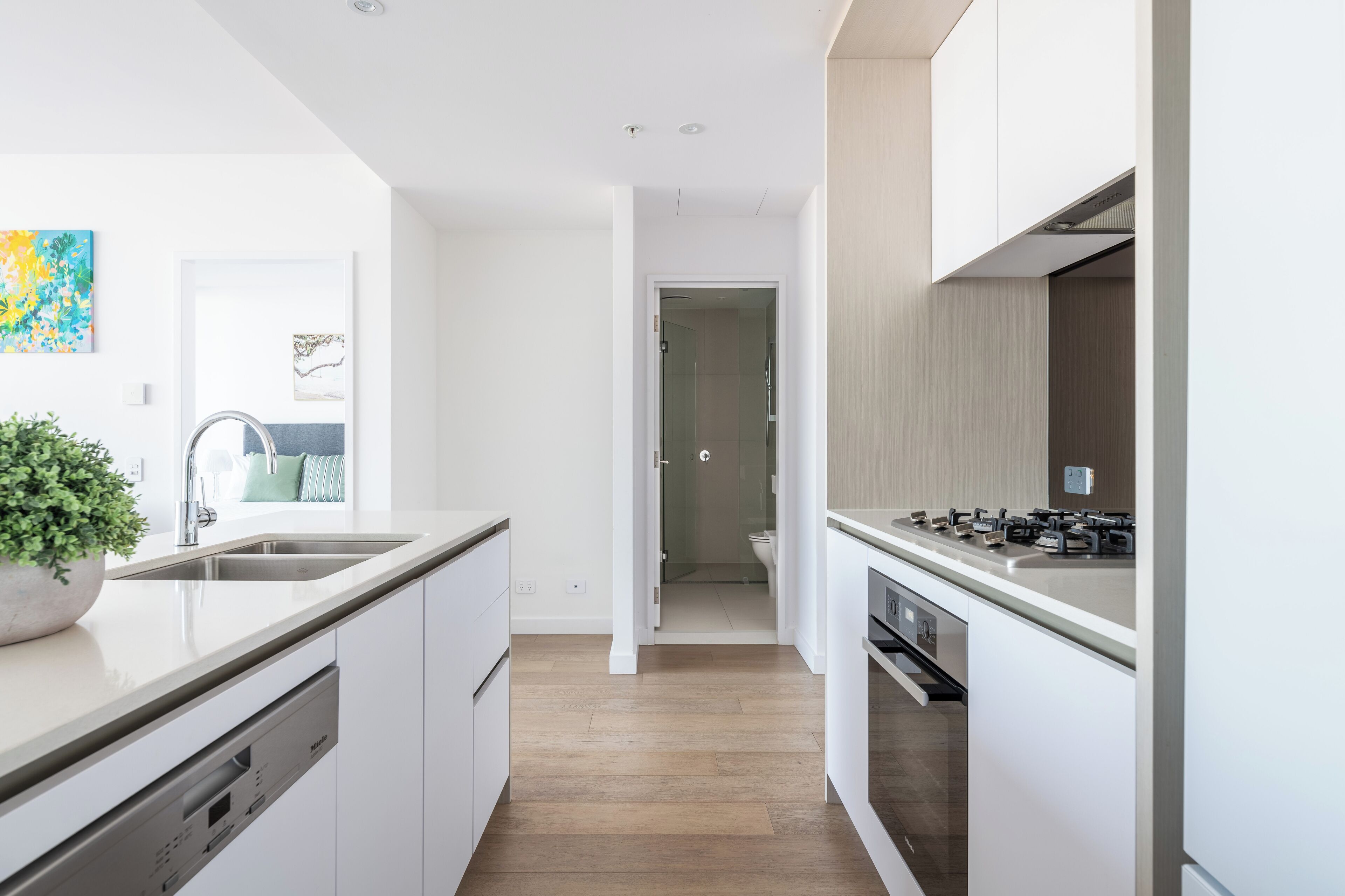 A modern kitchen with white cabinetry, a stainless steel sink, and a built-in stove.