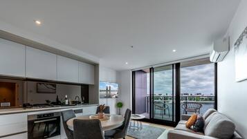 Un apartamento moderno con cocina, comedor y un balcón con vista a la ciudad.